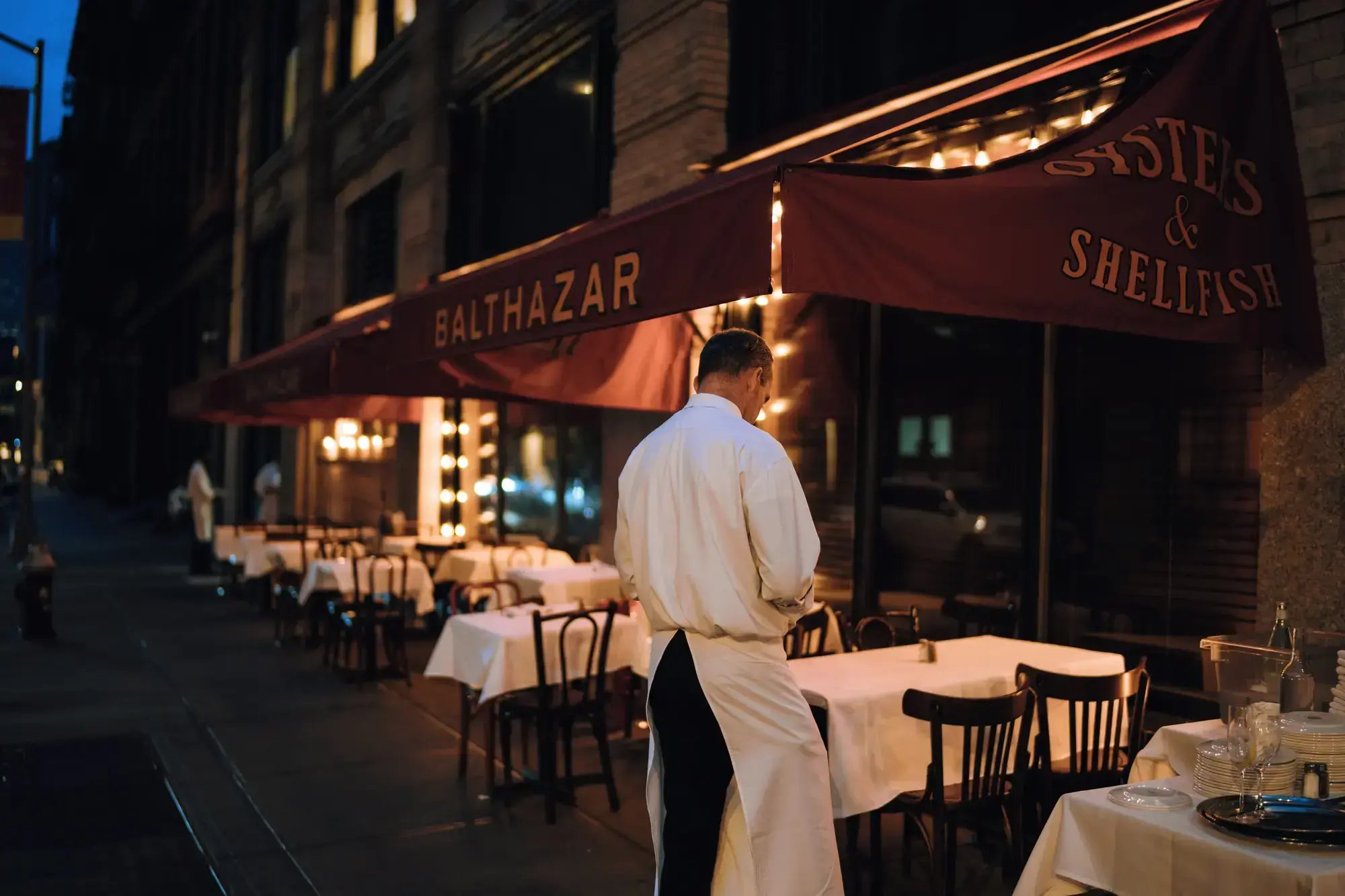Elegant outdoor dining area at night with waitstaff preparing tables.
