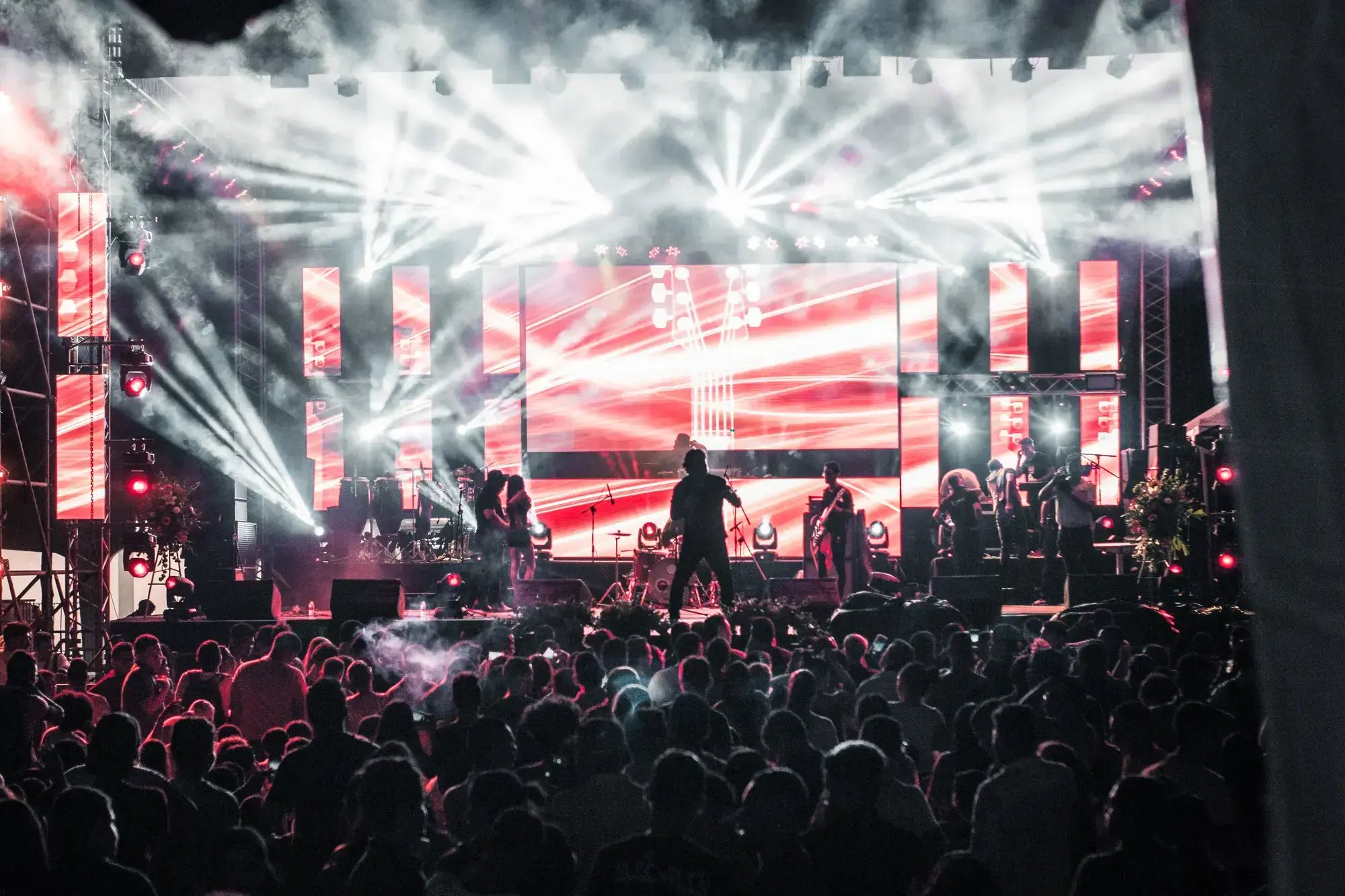Energetic live music concert featuring performers on a vibrant stage, captivating a large audience