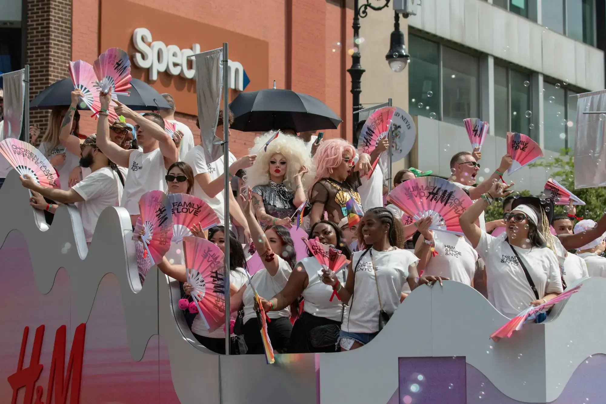 Pride parade participants celebrating on a colorful float in a city street.