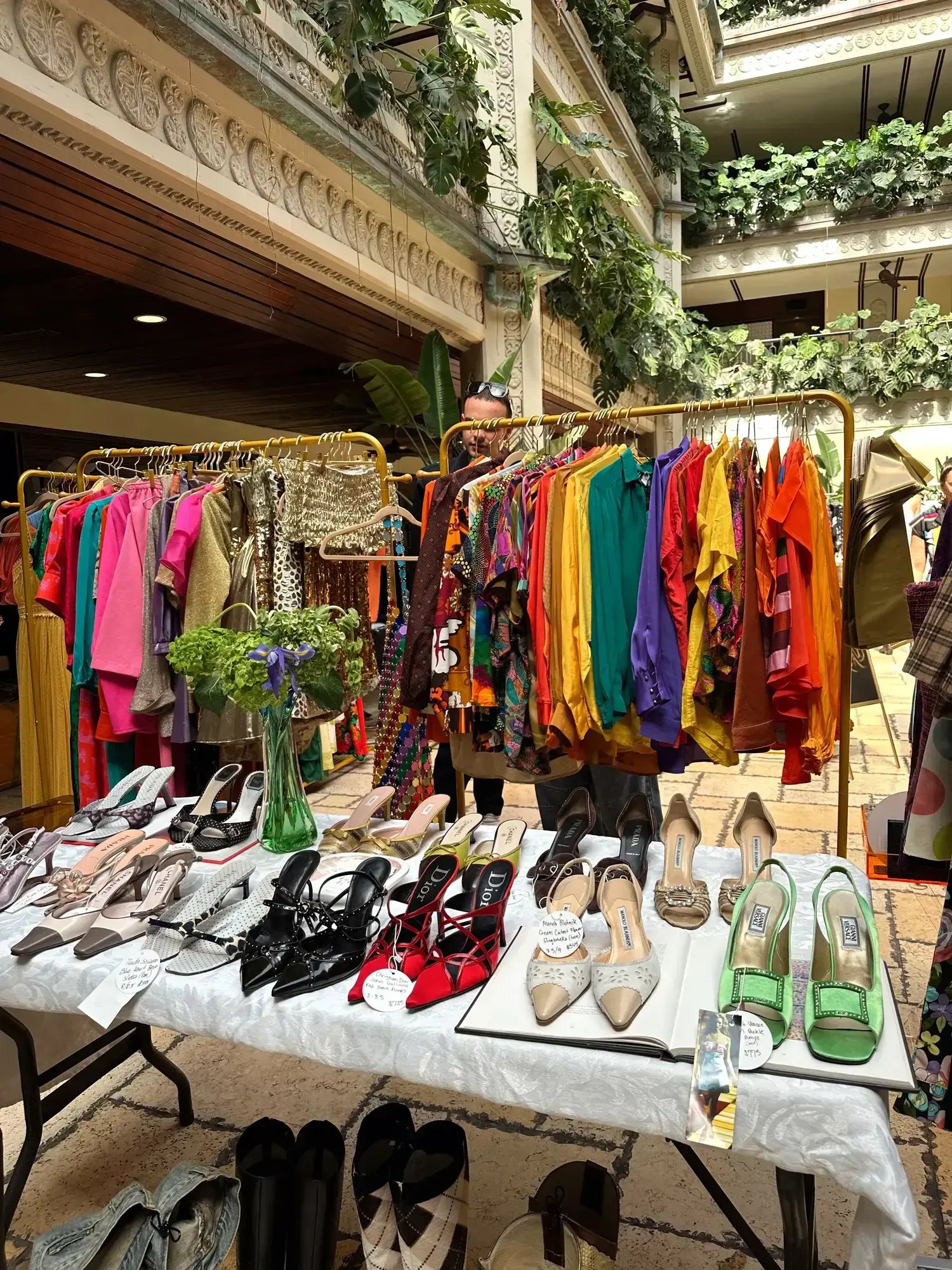 Vibrant vintage clothing and shoes displayed indoors with lush greenery