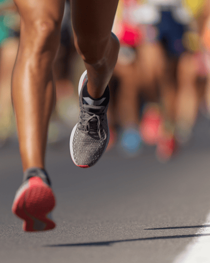 Close-up of a runner’s legs in motion during a marathon, with other participants in the background.