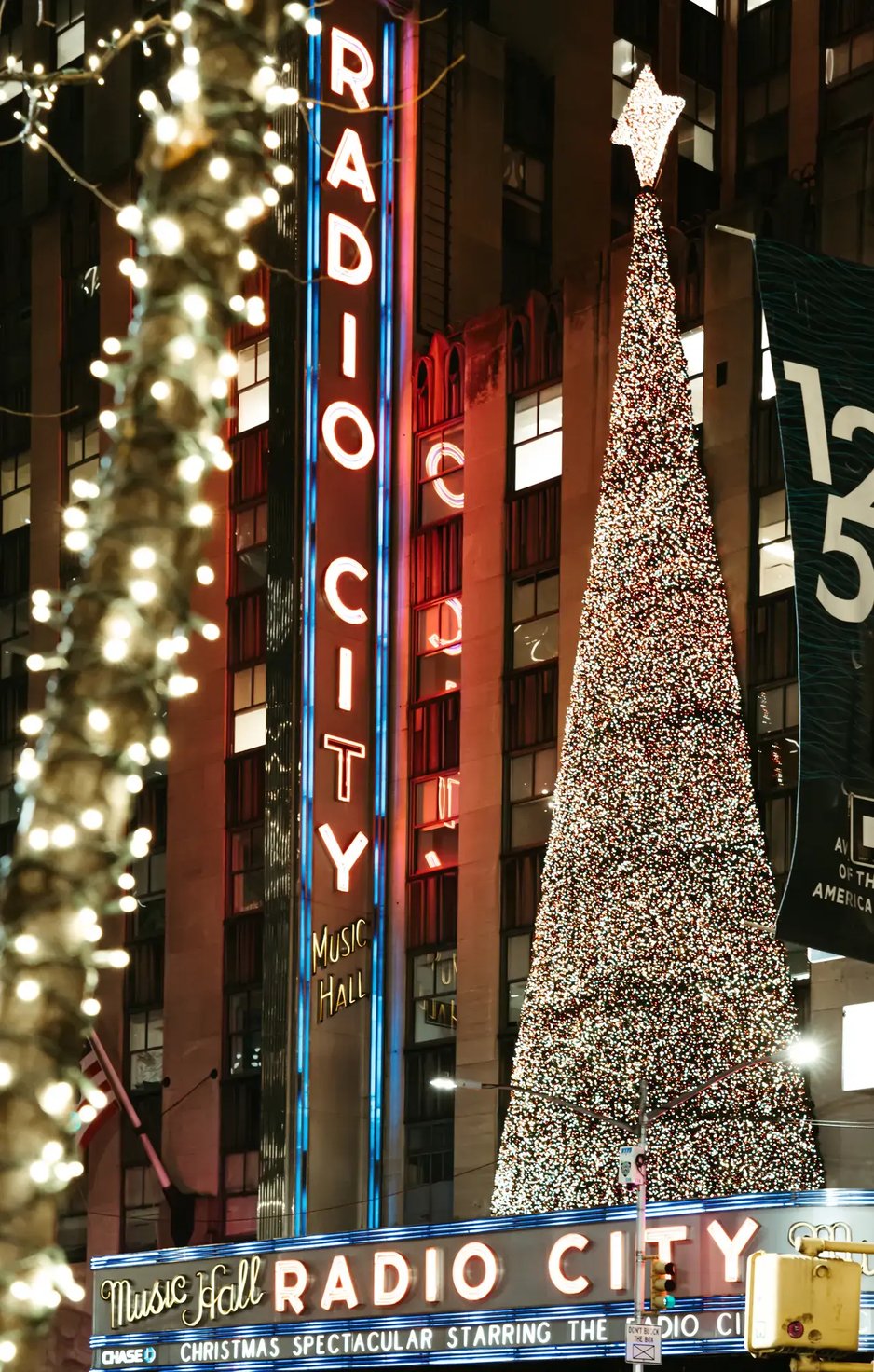 Illuminated Christmas tree and neon lights at Radio City Music Hall in New York City during the holiday season at night.