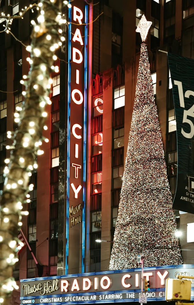 Illuminated Christmas tree and neon lights at Radio City Music Hall in New York City during the holiday season at night.