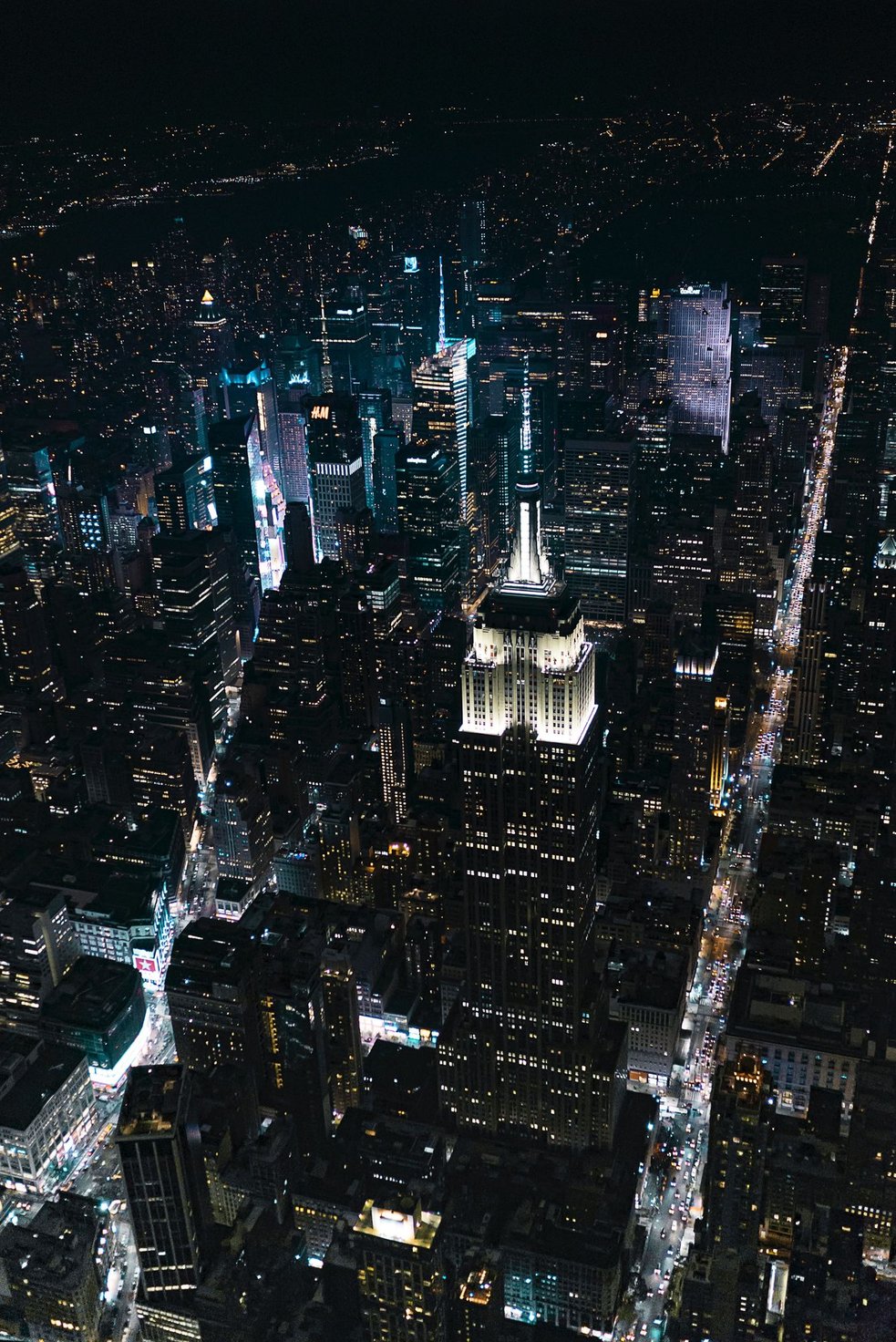 Vibrant Midtown Manhattan street scene glowing with neon lights at night.
