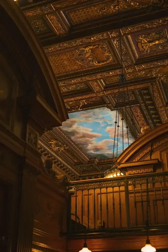 Intricate decorated ceiling in the New York Public Library with classic architecture and cloud mural.