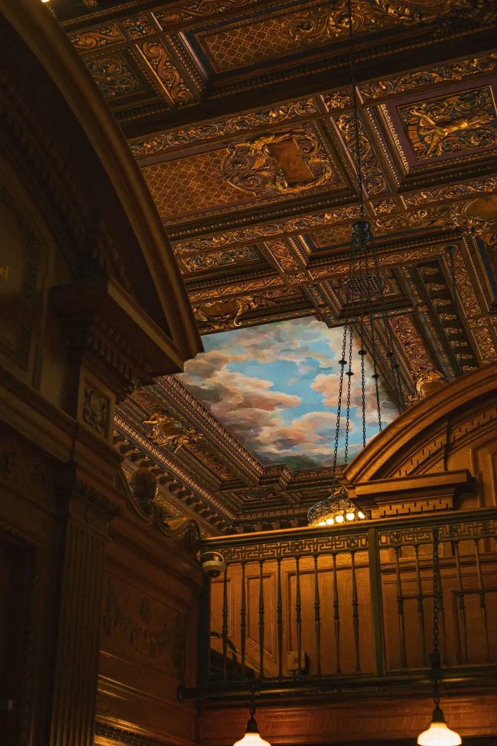 Intricate decorated ceiling in the New York Public Library with classic architecture and cloud mural.