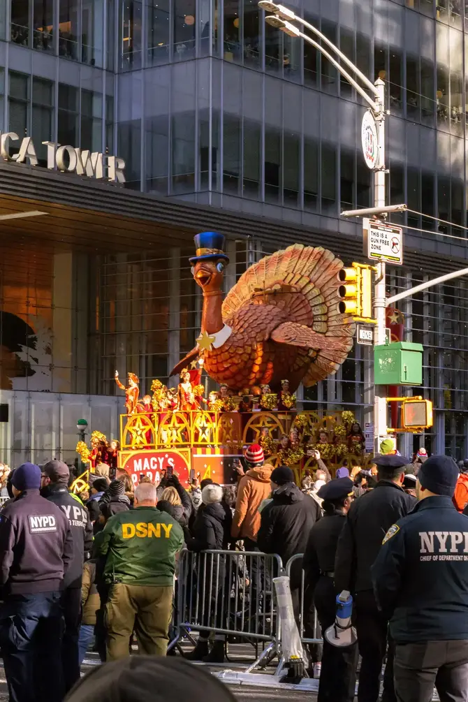 Colorful turkey float in the iconic Thanksgiving Parade in NYC with festive crowds.